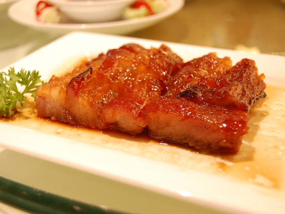 白い皿に盛ったつやのある薄切り叉焼と、小さなカーリーパセリ
