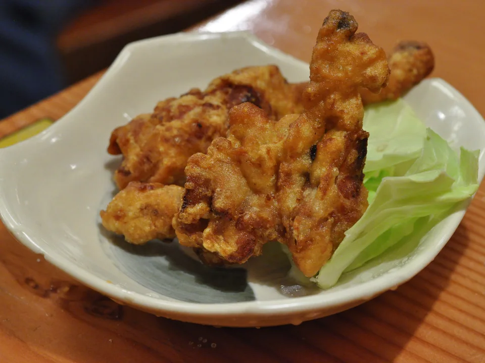 白い皿に盛ったカリッと黄金色の鶏の唐揚げと生の青キャベツの葉