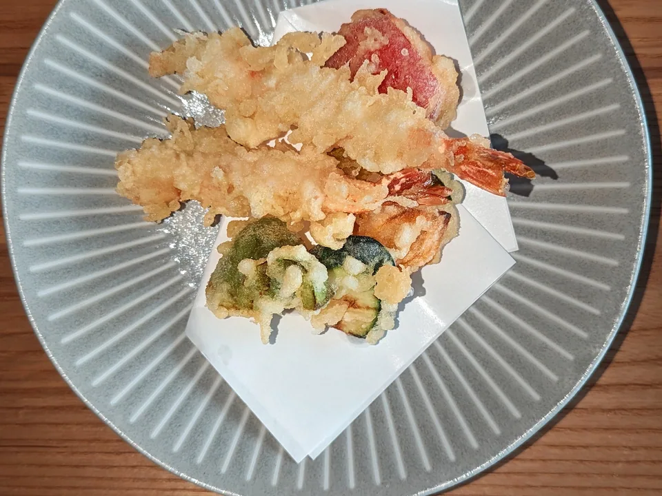大きな灰色の皿に盛ったえび2尾と野菜の天ぷら